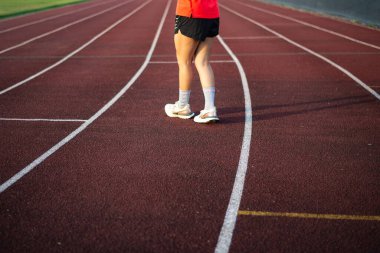 Koşu ayakkabısı giyen bir kadın yarış pistinde yürüyor.