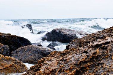 Denizde kayalar, kayalara çarpan dalgalar.