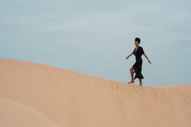 Bekar bir kadın doğada tek başına kumulda yürüyor.