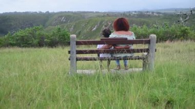 Rear view of mother and son sitting outdoors