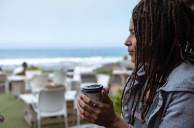 Kadın ısınmak için bardağı tutarken üşüyor.