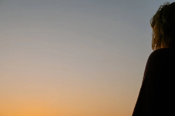 stock image Woman seen watchiing sunset shot from side