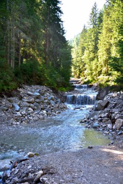 Valdaora 'da Brunst selinin suları ön planda arabayla geçilebilen bir nehirle vadiye iniyor.