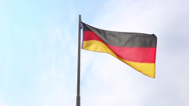 Alman bayrağı mavi gökyüzünün önünde, bayrak direğinde