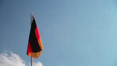 Mavi gökyüzünün önündeki bayrak direğine Almanya 'nın tekstil bayrağını asmak