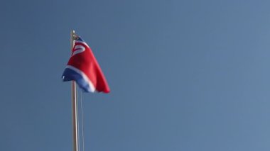 Mavi gökyüzünün önündeki bayrak direğinde Kuzey Kore 'nin tekstil bayrağı