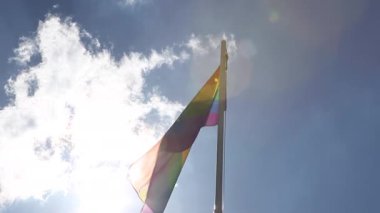 Gökkuşağı bayrağı bayrak direğine mavi gökyüzü önünde üzerinde