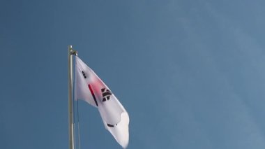 Güney Kore bayrağı mavi gökyüzünün önündeki bayrak direğinde