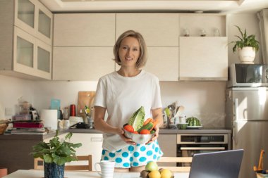 Mutfakta sebzeli güzel, pozitif gülümseyen bir kadın.