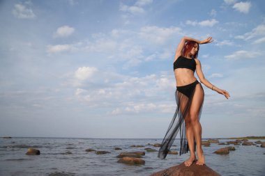 Denizin arka planında bikinili genç, narin bir kadın.