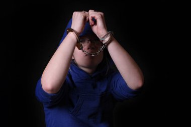 Siyah arka planda elleri kelepçeli bir adamın elleri.