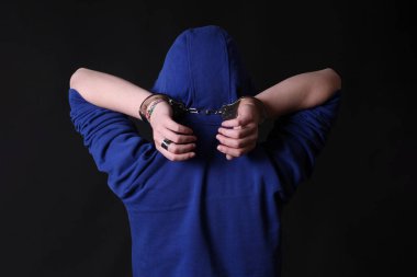 Siyah arka planda elleri kelepçeli bir adamın elleri.