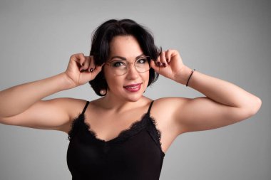 Gri arka planda giyinmiş genç bir kadın.