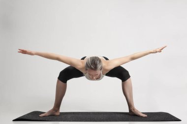 young beautiful yoga posing on light studio background