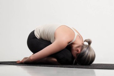 young beautiful yoga posing on light studio background