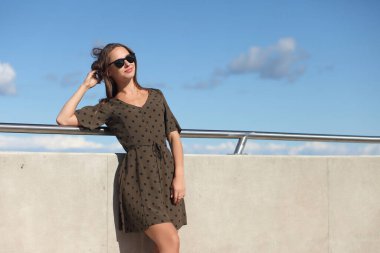 Deniz kenarındaki genç, narin kadın. Kıyafetler içinde poz veriyor.