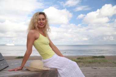 Deniz kenarında gülümseyen genç bir kadın.