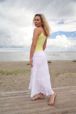 Deniz kenarında gülümseyen genç bir kadın.