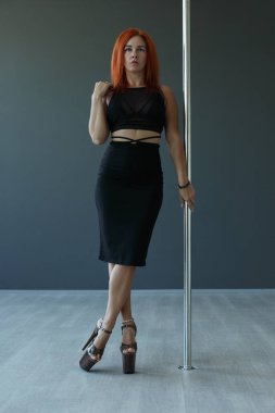 Genç esnek kız pilonun üzerinde pratik yapıyor.