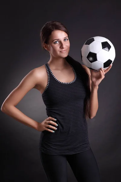 young woman with soccer ball on black background