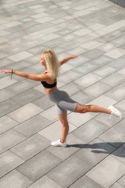 Spor figürlü genç bir kadın esneme hareketleri yapıyor.