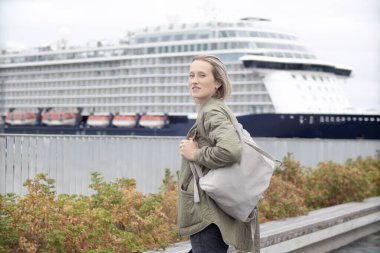 Deniz kenarında genç bir turist yolcu gemisi bekliyor.