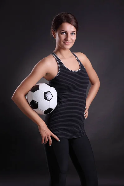 young woman with soccer ball on black background