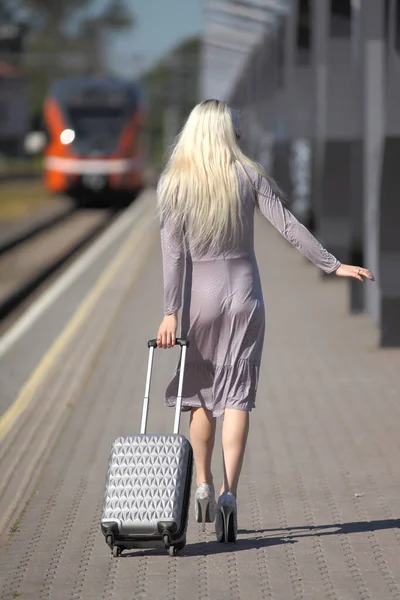 火车站里穿着连衣裙 提着手提箱的年轻女子 — 图库照片