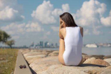 young beautiful woman in a white swimsuit against the sky