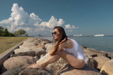 young beautiful woman in a white swimsuit against the sky