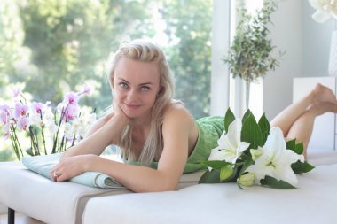 Çekici ve gülümseyen bir kadın masaj paspasında yatıyor.