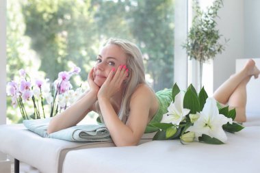 Çekici ve gülümseyen bir kadın masaj paspasında yatıyor.