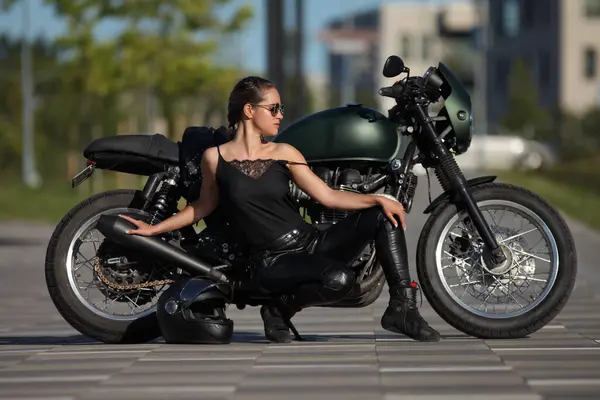 黑色摩托车上迷人的年轻女子的画像 图库图片