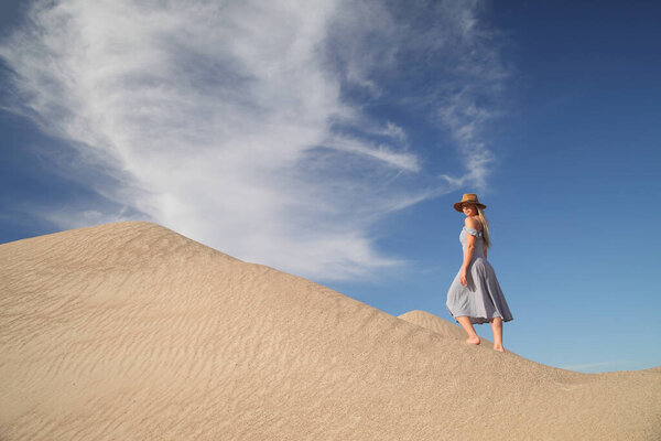 young woman on sandy mountain posing in dress
