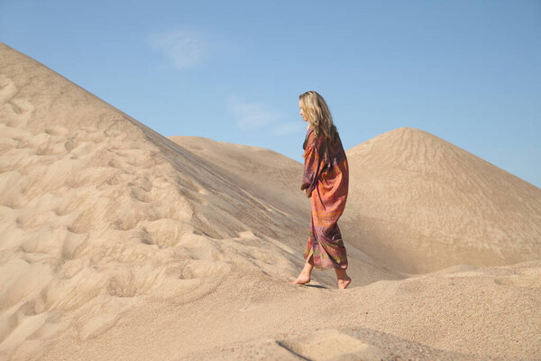 young woman on sandy mountain posing in dress