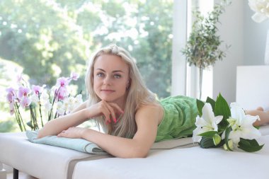 Çekici ve gülümseyen bir kadın masaj paspasında yatıyor.