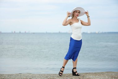 Deniz kenarında şapkası olan güzel bir kadın.