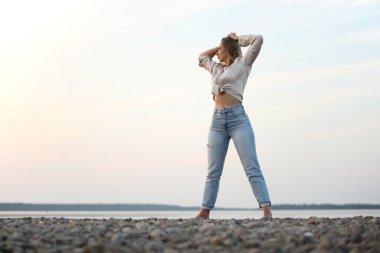 Deniz kenarında poz veren güzel bir kadın.