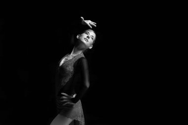 Genç bayan artistik patinajcı koyu arkaplanda poz veriyor