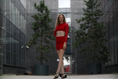 Kırmızı bluzlu ve etekli zayıf bir kadın.