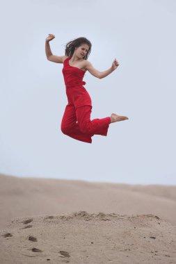 Genç bayan kumların üzerinde kırmızı tulumlu.