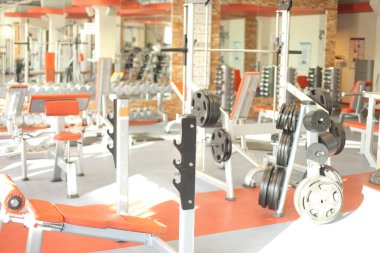 Ağırlıkları, bankları ve spor aletleri olan parlak spor salonunun fotoğrafı.