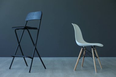 Siyah katlanır sandalye ve beyaz modern sandalye ahşap zeminde.