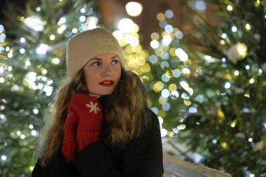 Arka planda festival ışıkları olan kışın giyinmiş kadın..