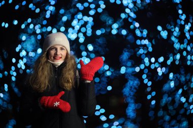Arka planda festival ışıkları olan kışın giyinmiş kadın..