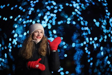 Arka planda festival ışıkları olan kışın giyinmiş kadın..