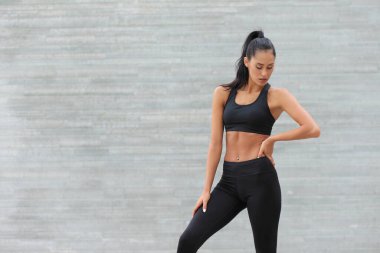 Siyah spor giyim giymiş genç ve güzel bir kadın.