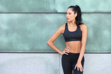 Siyah spor giyim giymiş genç ve güzel bir kadın.