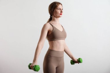 Gri arka planda dambılları olan zayıf genç bir kadın..