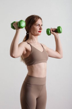 Gri arka planda dambılları olan zayıf genç bir kadın..